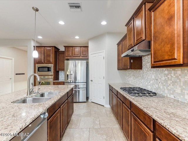 3872 W Sonoma Ranch Pl, Marana, AZ 85658 - kitchen with stainless steel appliances, under cabinet range hood, hanging light fixtures, tasteful backsplash, and light stone countertops