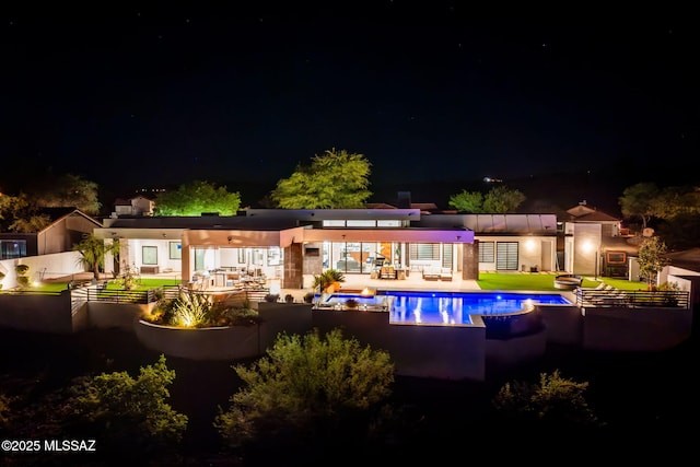 379 Camino A Las Casitas, Rio Rico, AZ 85648 - back of house at night with an outdoor pool, a patio area, and an outdoor living space
