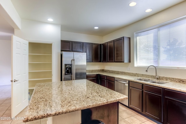 8348 N Mountain Stone Pine Way, Tucson, AZ 85743 - kitchen featuring appliances with stainless steel finishes, light tile patterned floors, light stone counters, dark brown cabinetry, and a center island