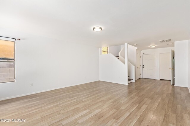 3969 E Agate Knoll Dr, Tucson, AZ 85756 - unfurnished living room featuring light wood-type flooring, stairs, and healthy amount of natural light