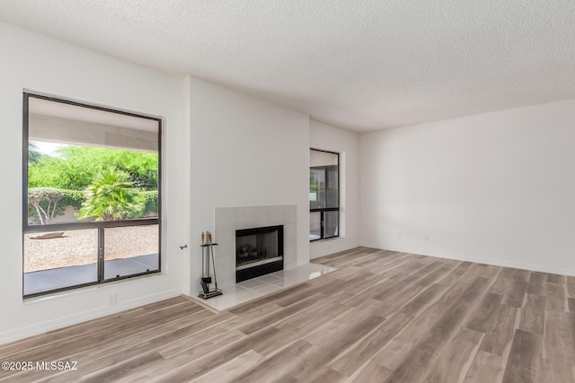 64161 E Santa Catalina Ct, Saddlebrooke, AZ 85739 - unfurnished living room with a textured ceiling, wood finished floors, and a tile fireplace