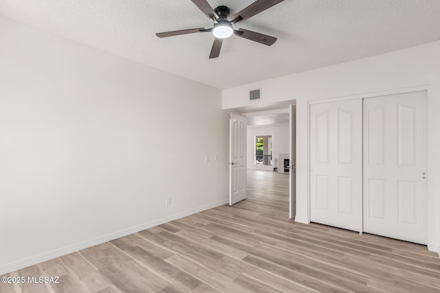 64161 E Santa Catalina Ct, Saddlebrooke, AZ 85739 - unfurnished bedroom featuring light wood-style floors, a textured ceiling, a closet, and ceiling fan