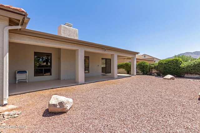 64161 E Santa Catalina Ct, Saddlebrooke, AZ 85739 - back of house with a chimney, a patio, stucco siding, and a mountain view
