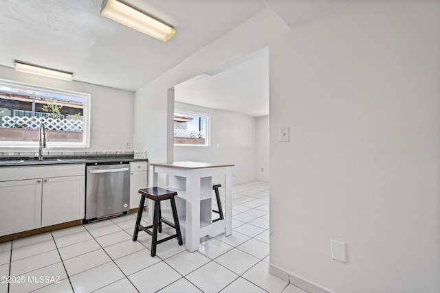 1818 E Mitchell St, Tucson, AZ 85719 - kitchen with dishwasher, dark countertops, light tile patterned floors, and white cabinets