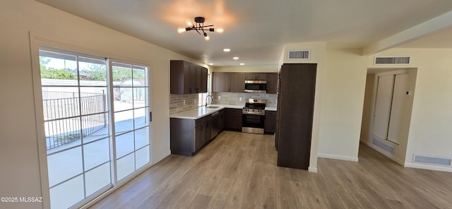 2215 E Bantam Rd, Tucson, AZ 85706 - kitchen with stainless steel appliances, light wood-style floors, decorative backsplash, dark brown cabinetry, and light countertops