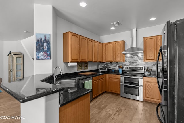 977 S Limestone St, Benson, AZ 85602 - kitchen featuring stainless steel appliances, wall chimney range hood, a peninsula, light wood-style flooring, and dark stone counters