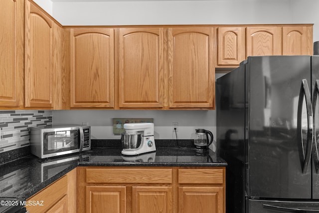 977 S Limestone St, Benson, AZ 85602 - kitchen featuring freestanding refrigerator, stainless steel microwave, dark stone countertops, and decorative backsplash