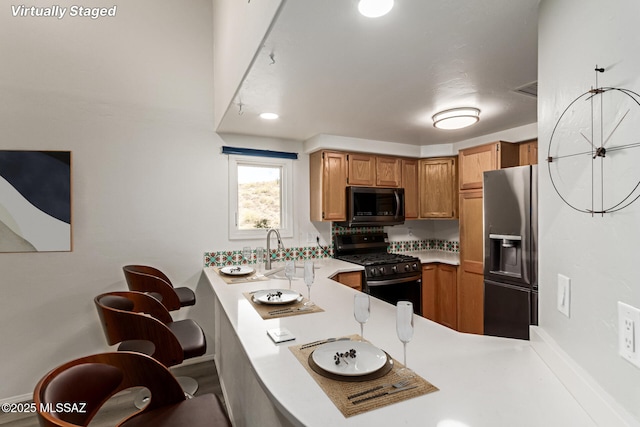 467 S Stephanie Loop, Tucson, AZ 85745 - kitchen featuring stainless steel appliances, light countertops, a peninsula, and brown cabinets
