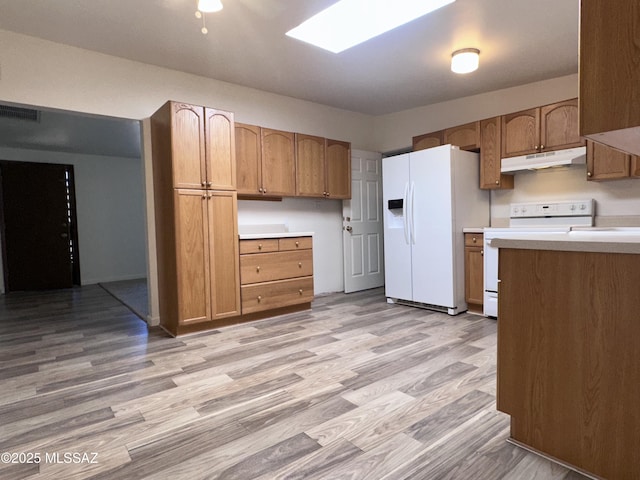 1339 W Pastime Rd, Tucson, AZ 85705 - kitchen featuring white appliances, under cabinet range hood, light countertops, light wood-style floors, and brown cabinets