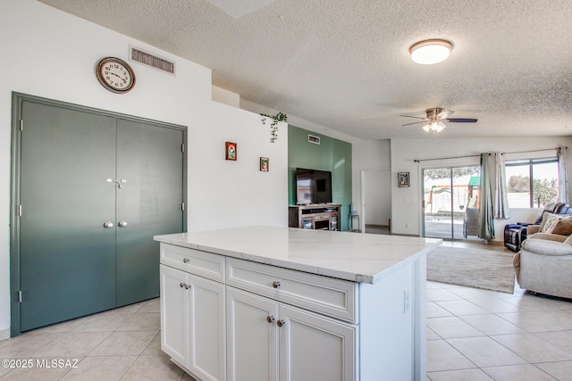 6075 N Applesauce Ct, Tucson, AZ 85741 - kitchen featuring open floor plan, a textured ceiling, ceiling fan, light tile patterned floors, and white cabinetry