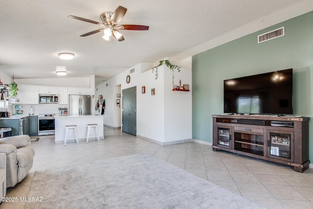 6075 N Applesauce Ct, Tucson, AZ 85741 - living room featuring vaulted ceiling, light tile patterned floors, a textured ceiling, and a ceiling fan