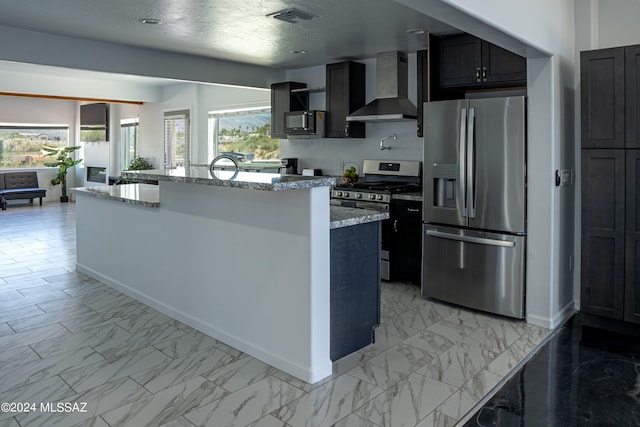 5051 N Hillcrest Dr, Tucson, AZ 85704 - kitchen with appliances with stainless steel finishes, wall chimney range hood, light marble finish floors, light stone counters, and a center island with sink
