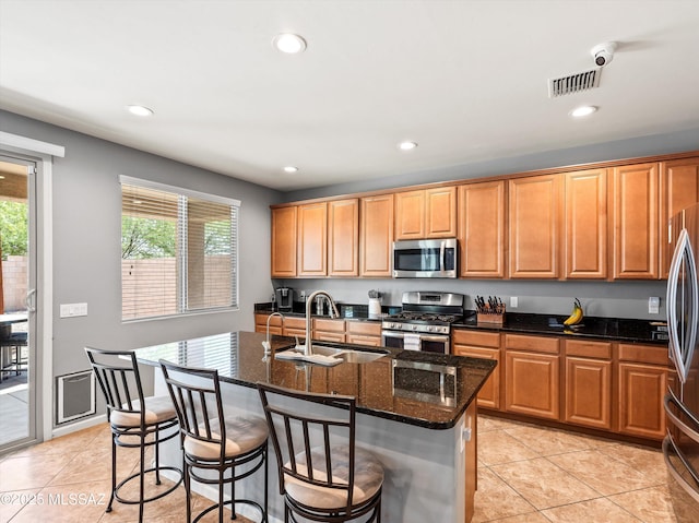11471 E Squash Blossom Loop, Tucson, AZ 85747 - kitchen with appliances with stainless steel finishes, dark stone counters, a center island with sink, light tile patterned floors, and recessed lighting