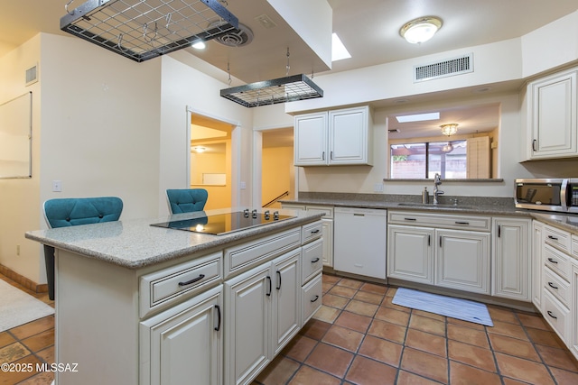 2000 E Campbell Ter, Tucson, AZ 85718 - kitchen featuring stainless steel microwave, dishwasher, black electric stovetop, a kitchen island, and white cabinetry