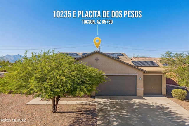 10235 E Placita De Dos Pesos, Tucson, AZ 85730 - view of front of house with a garage, driveway, stucco siding, roof mounted solar panels, and a tile roof