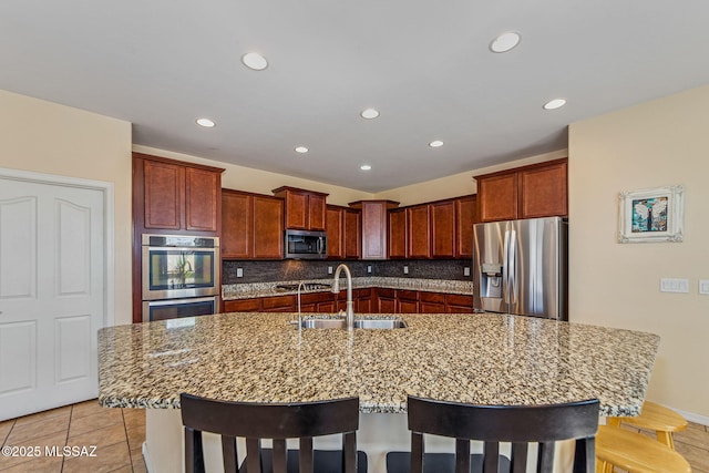 10235 E Placita De Dos Pesos, Tucson, AZ 85730 - kitchen with appliances with stainless steel finishes, recessed lighting, a kitchen breakfast bar, decorative backsplash, and light stone counters
