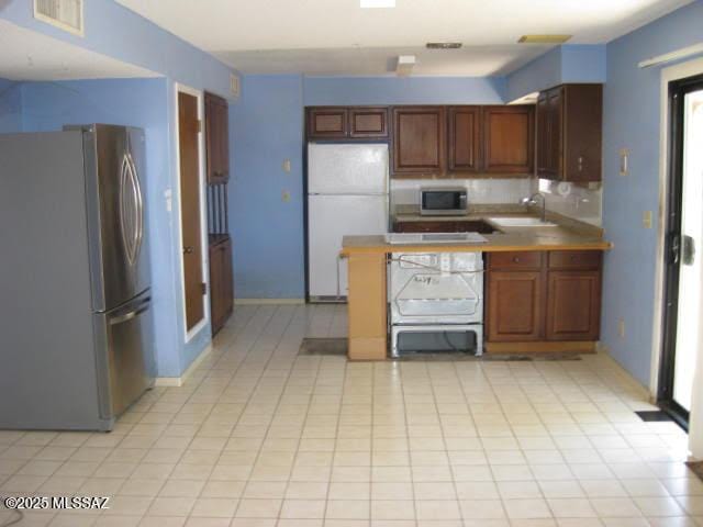 3885 W Mars St, Tucson, AZ 85741 - kitchen with appliances with stainless steel finishes, a peninsula, light tile patterned floors, and tasteful backsplash