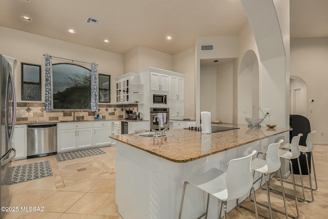 6859 N Placita Chula Vis, Tucson, AZ 85704 - kitchen with stainless steel appliances, light stone countertops, tasteful backsplash, white cabinetry, and arched walkways