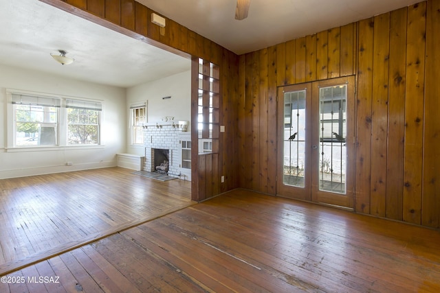 642 E 2nd St, Tucson, AZ 85705 - unfurnished living room featuring french doors, hardwood / wood-style floors, a fireplace, and wooden walls