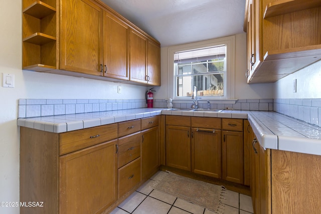 642 E 2nd St, Tucson, AZ 85705 - kitchen with open shelves, light tile patterned floors, brown cabinets, and tile countertops