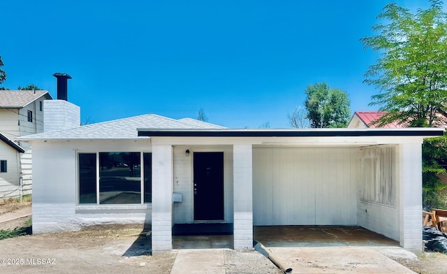 1105 S 1st Ave, Safford, AZ 85546 - view of front of house featuring a shingled roof, a chimney, brick siding, and an attached carport