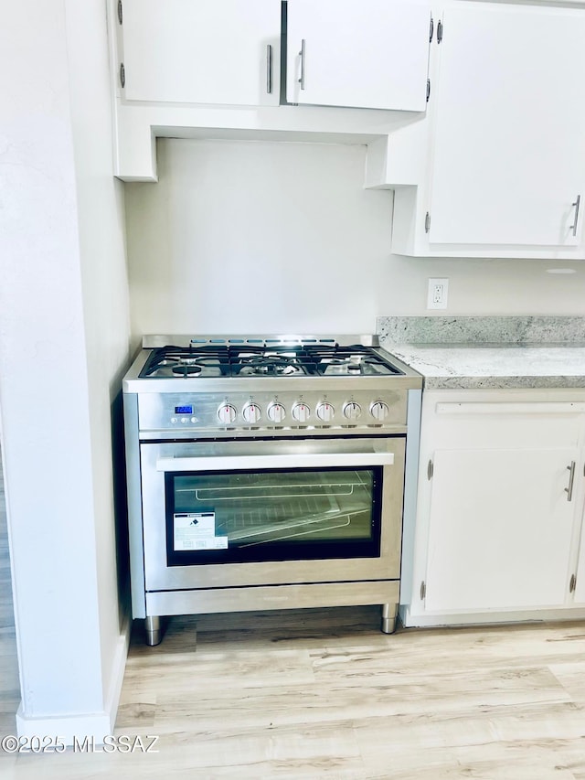 1105 S 1st Ave, Safford, AZ 85546 - kitchen with gas range, white cabinets, light wood-style flooring, and light stone counters