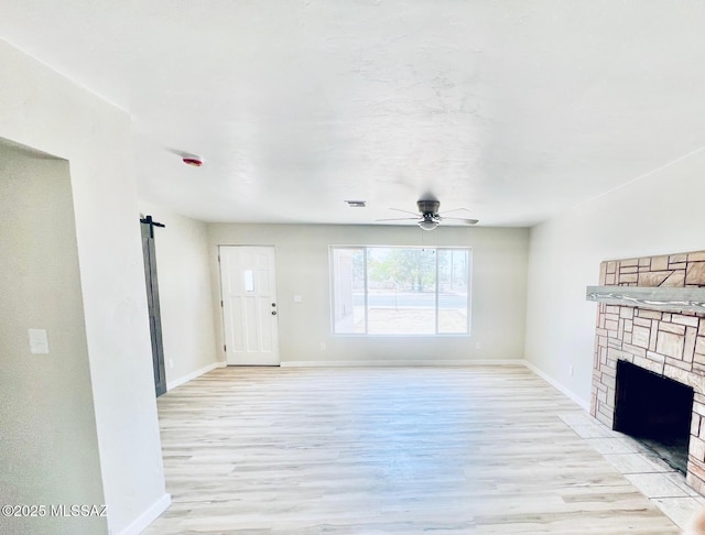 1105 S 1st Ave, Safford, AZ 85546 - unfurnished living room featuring light wood finished floors, a ceiling fan, a barn door, and a fireplace