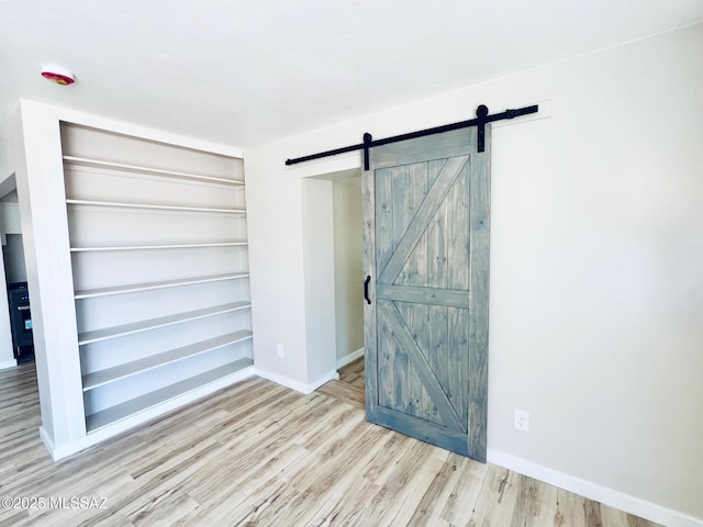 1105 S 1st Ave, Safford, AZ 85546 - unfurnished bedroom featuring a barn door and wood finished floors