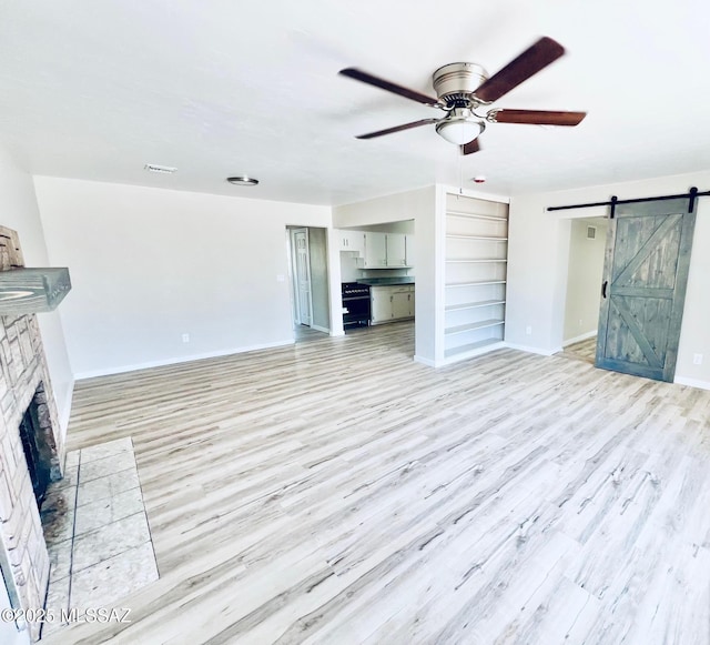 1105 S 1st Ave, Safford, AZ 85546 - unfurnished living room featuring a barn door, ceiling fan, light wood finished floors, and a fireplace