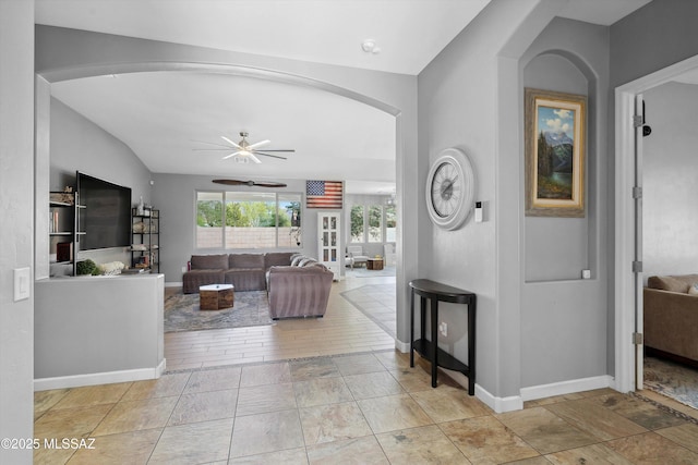 8470 N Gaetano Loop, Tucson, AZ 85742 - living room with ceiling fan, arched walkways, vaulted ceiling, and stone finish flooring
