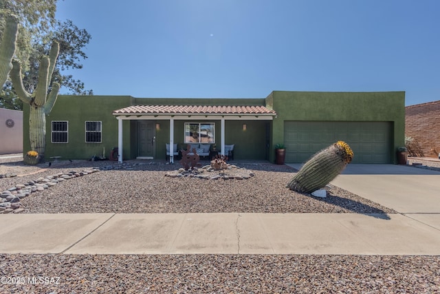 1120 N La Canoa, Green Valley, AZ 85614 - pueblo-style house with concrete driveway, an attached garage, stucco siding, covered porch, and a tile roof