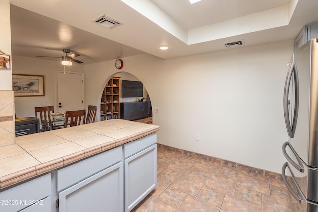1120 N La Canoa, Green Valley, AZ 85614 - kitchen featuring freestanding refrigerator, arched walkways, a raised ceiling, a ceiling fan, and tile countertops