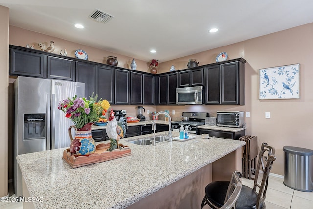 1123 E Lumberjack Trl, Sahuarita, AZ 85629 - kitchen with appliances with stainless steel finishes, light tile patterned floors, light stone countertops, dark cabinets, and a kitchen breakfast bar