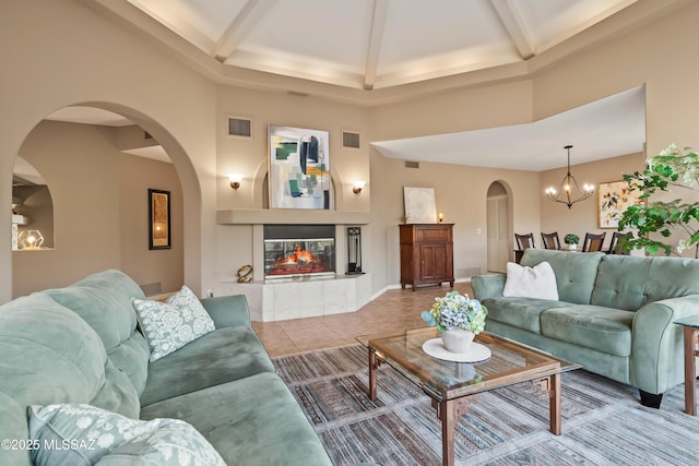 6265 N Jochums Dr, Tucson, AZ 85718 - living room featuring a high ceiling, arched walkways, beamed ceiling, a chandelier, and tile patterned flooring
