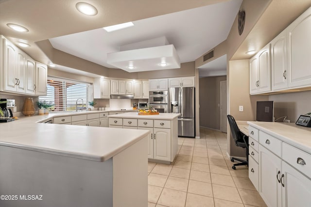 6265 N Jochums Dr, Tucson, AZ 85718 - kitchen with appliances with stainless steel finishes, a peninsula, white cabinetry, light tile patterned floors, and light countertops
