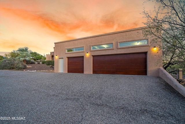 6265 N Jochums Dr, Tucson, AZ 85718 - view of front of property with stucco siding, a garage, and gravel driveway