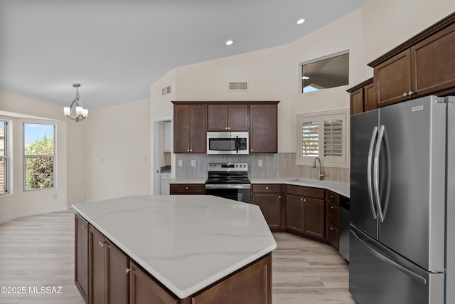 1993 E Desert Lark Pass, Green Valley, AZ 85614 - kitchen featuring appliances with stainless steel finishes, light wood finished floors, a kitchen island, a chandelier, and tasteful backsplash