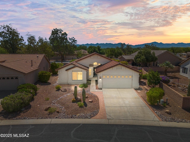 1993 E Desert Lark Pass, Green Valley, AZ 85614 - view of front of house with concrete driveway, an attached garage, a mountain view, and stucco siding