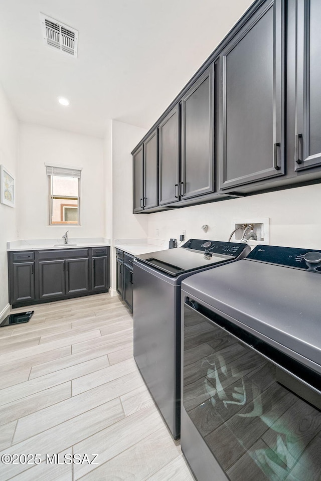 1144 S Castar Dr, Tucson, AZ 85745 - washroom featuring cabinet space, washing machine and clothes dryer, and light wood-style flooring