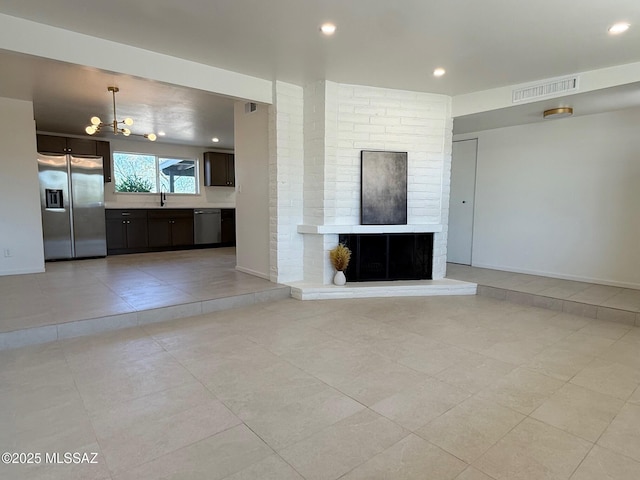 8324 E Beverly St, Tucson, AZ 85710 - unfurnished living room featuring a chandelier, light tile patterned flooring, recessed lighting, and a brick fireplace