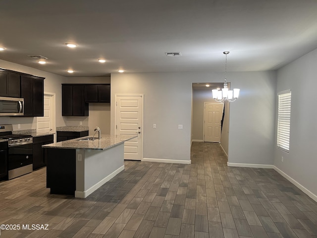 3306 N Baby Bruno Way, Tucson, AZ 85745 - kitchen with appliances with stainless steel finishes, light stone counters, dark wood-style floors, a kitchen island with sink, and recessed lighting
