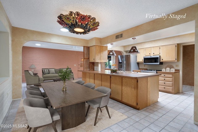 149 E La Huerta, Green Valley, AZ 85614 - kitchen with appliances with stainless steel finishes, a peninsula, a textured ceiling, light tile patterned flooring, and light brown cabinets