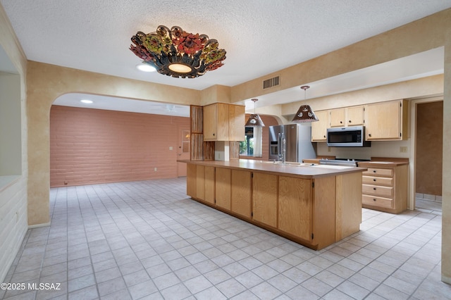 149 E La Huerta, Green Valley, AZ 85614 - kitchen with stainless steel appliances, a textured ceiling, a peninsula, light brown cabinets, and pendant lighting