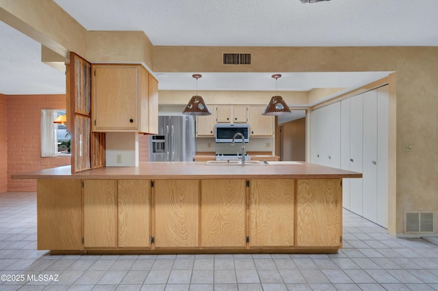 149 E La Huerta, Green Valley, AZ 85614 - kitchen with stainless steel fridge, light countertops, a peninsula, light tile patterned flooring, and hanging light fixtures
