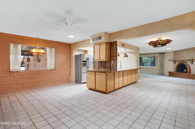 149 E La Huerta, Green Valley, AZ 85614 - kitchen with stainless steel refrigerator with ice dispenser, open floor plan, a ceiling fan, light brown cabinetry, and brick wall