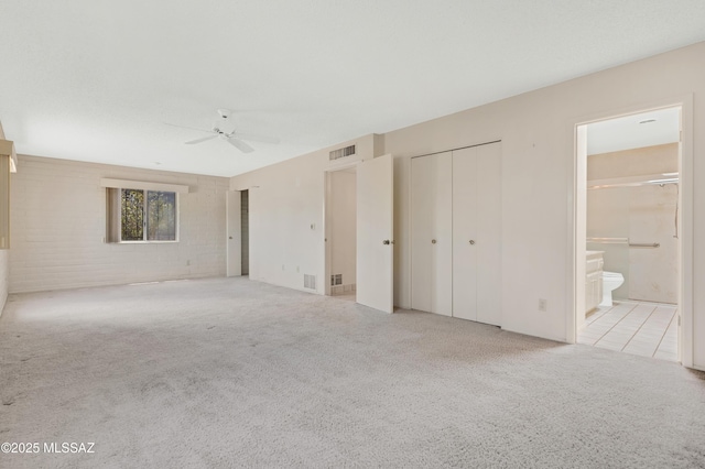 149 E La Huerta, Green Valley, AZ 85614 - unfurnished bedroom featuring carpet flooring, two closets, ensuite bathroom, brick wall, and a ceiling fan
