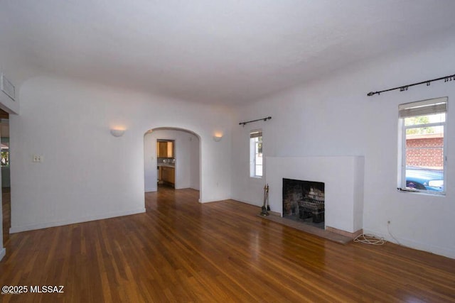 1816 E Waverly St, Tucson, AZ 85719 - unfurnished living room with wood finished floors, arched walkways, a fireplace, and healthy amount of natural light