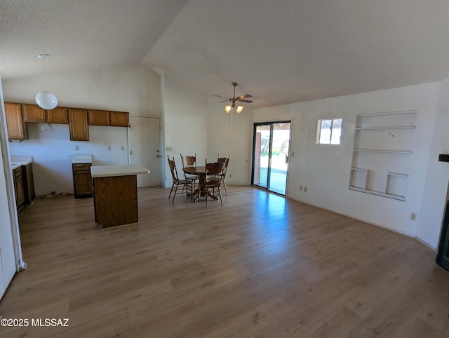7088 S Camino Grande, Tucson, AZ 85746 - kitchen with brown cabinets, a center island, light wood-style floors, vaulted ceiling, and open floor plan