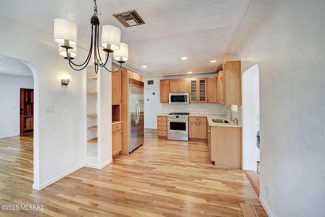 2421 E Drachman St, Tucson, AZ 85719 - kitchen with stainless steel appliances, light wood finished floors, arched walkways, light countertops, and tasteful backsplash