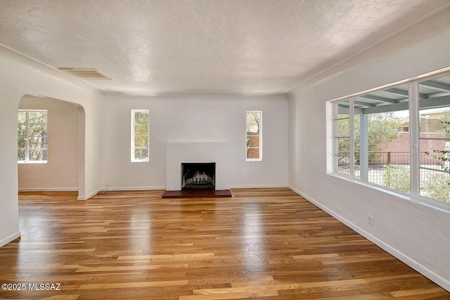 2421 E Drachman St, Tucson, AZ 85719 - unfurnished living room featuring healthy amount of natural light, arched walkways, light wood-type flooring, and a fireplace